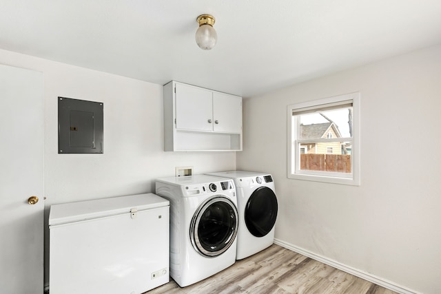 laundry area featuring baseboards, light wood-style floors, cabinet space, electric panel, and washing machine and clothes dryer