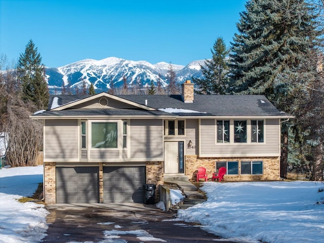 raised ranch with brick siding, a chimney, a mountain view, a garage, and driveway