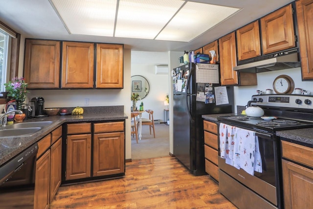 kitchen with under cabinet range hood, a sink, black appliances, brown cabinetry, and dark countertops