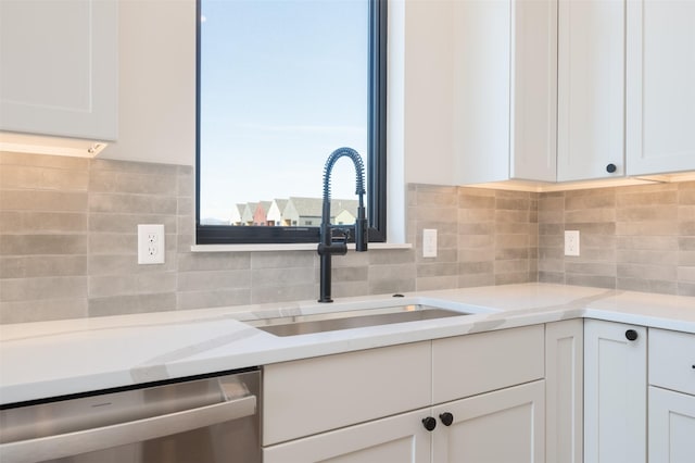 kitchen with dishwasher, tasteful backsplash, a sink, and white cabinets