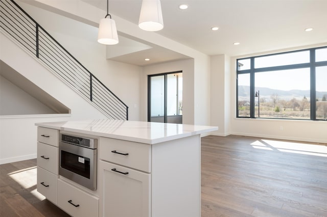 kitchen featuring white cabinetry, light countertops, oven, and wood finished floors