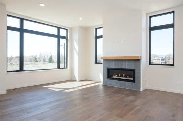 unfurnished living room featuring wood finished floors, recessed lighting, a tile fireplace, and baseboards