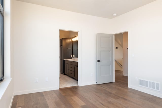 unfurnished bedroom featuring visible vents, baseboards, and wood finished floors