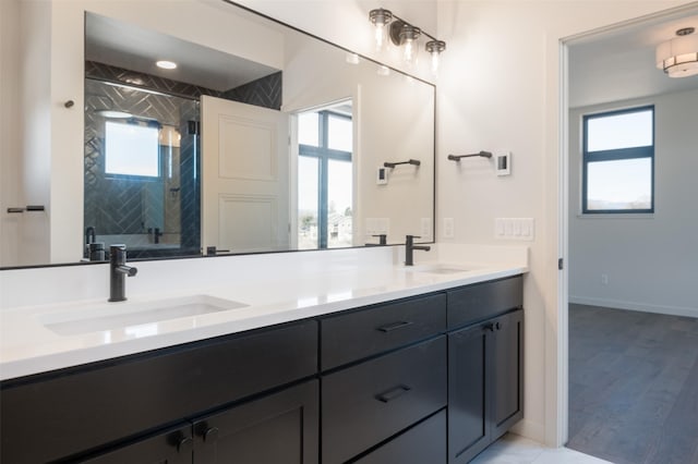 bathroom with a stall shower, a sink, baseboards, and double vanity