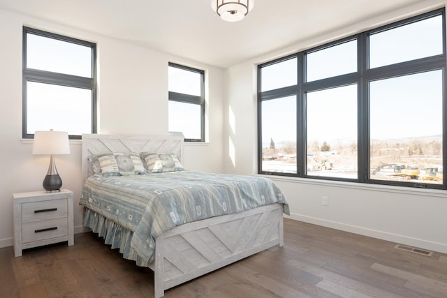 bedroom with baseboards, visible vents, and wood finished floors