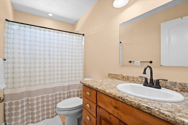 full bath with a textured wall, curtained shower, vanity, and toilet