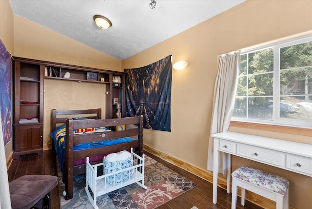 bedroom featuring lofted ceiling, baseboards, and wood finished floors