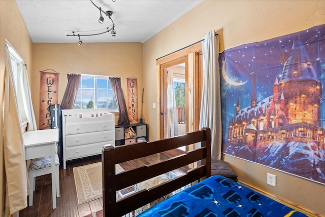 bedroom featuring wood finished floors and track lighting