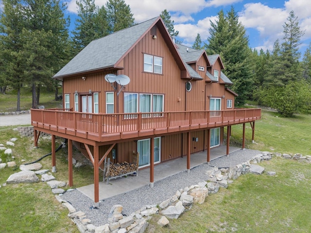 rear view of property with a patio area, a lawn, a deck, and roof with shingles