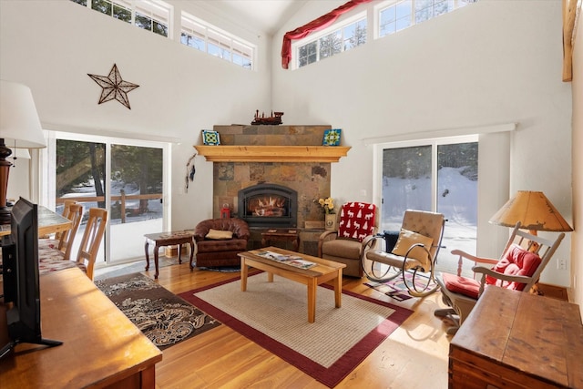 living area featuring high vaulted ceiling, a lit fireplace, and wood finished floors