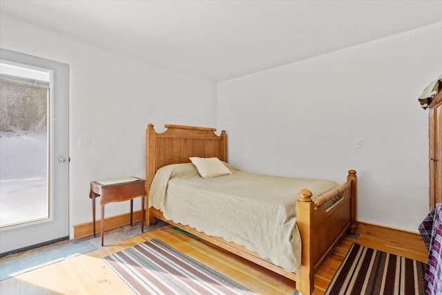 bedroom featuring multiple windows, baseboards, and wood finished floors