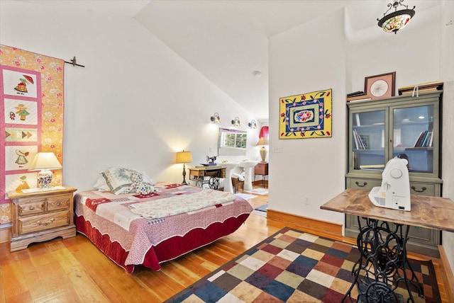 bedroom featuring high vaulted ceiling and wood finished floors