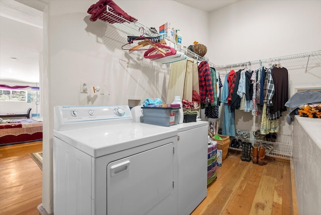 clothes washing area with laundry area, light wood-style flooring, and separate washer and dryer