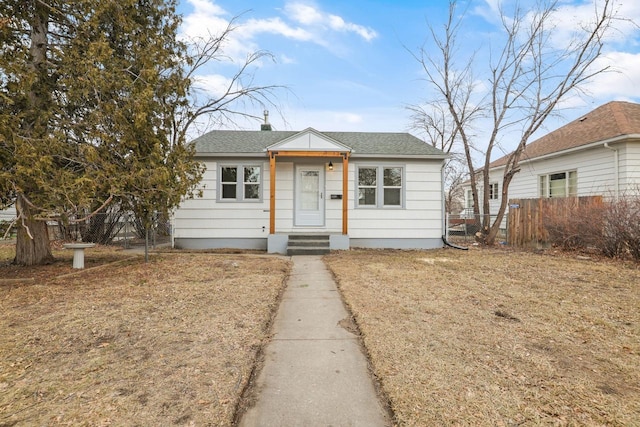 bungalow-style house featuring roof with shingles and fence