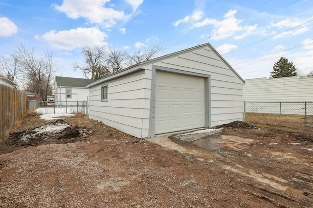 detached garage featuring fence and driveway