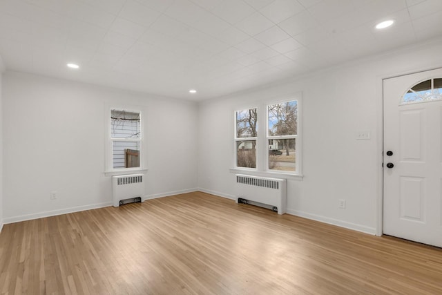 entrance foyer with radiator heating unit, light wood-type flooring, and a wealth of natural light