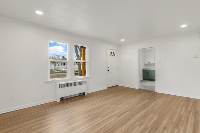 unfurnished living room with baseboards, radiator heating unit, recessed lighting, and light wood-style floors