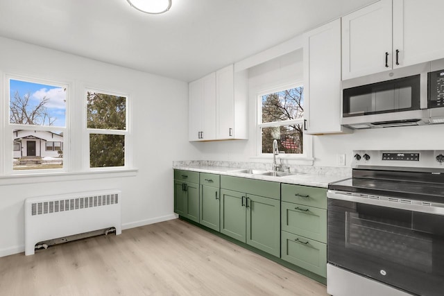 kitchen featuring stainless steel appliances, a sink, green cabinets, light countertops, and radiator heating unit