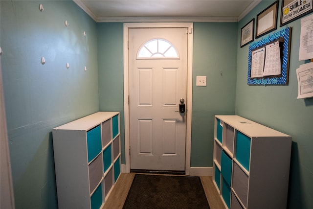 foyer entrance with crown molding, baseboards, and wood finished floors