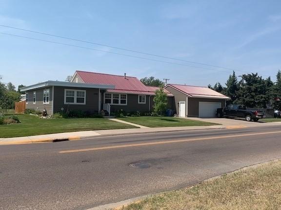 ranch-style home featuring a garage, concrete driveway, and a front lawn