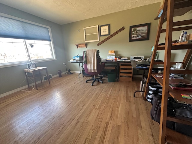 home office with visible vents, a textured ceiling, baseboards, and wood finished floors