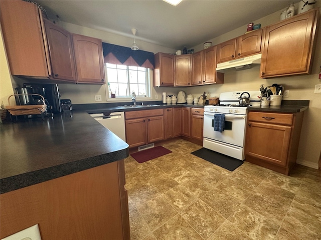 kitchen featuring brown cabinets, dark countertops, a sink, white appliances, and under cabinet range hood