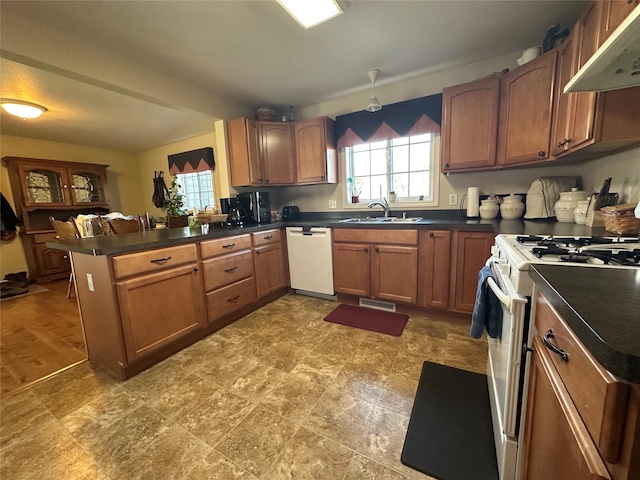 kitchen featuring dark countertops, white appliances, under cabinet range hood, and a sink