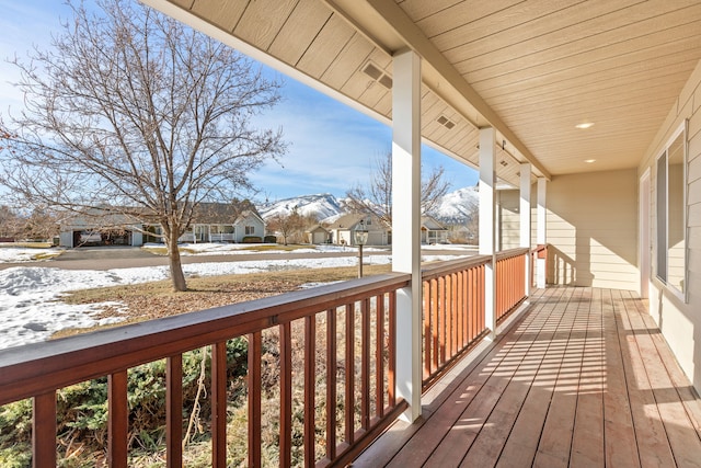 snow covered deck featuring a porch and a residential view