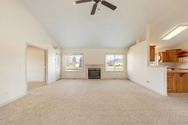 unfurnished living room featuring light colored carpet, a ceiling fan, a glass covered fireplace, high vaulted ceiling, and baseboards