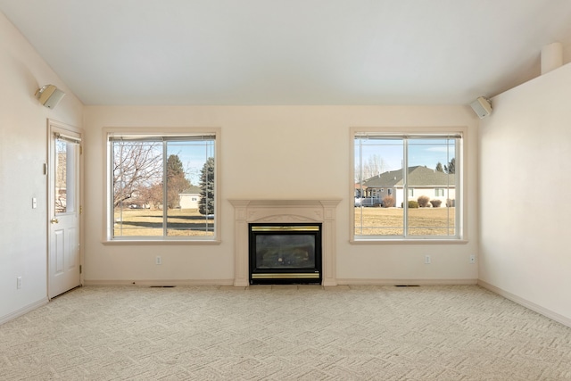 unfurnished living room featuring carpet floors, a glass covered fireplace, and a healthy amount of sunlight