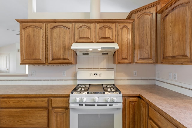 kitchen with light countertops, white gas range, brown cabinets, and under cabinet range hood