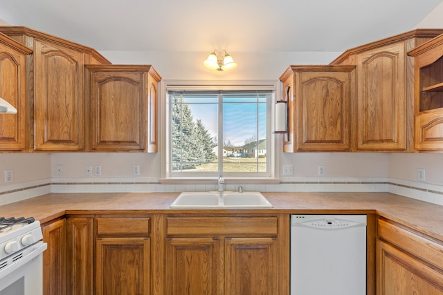 kitchen featuring brown cabinetry, white appliances, light countertops, and a sink