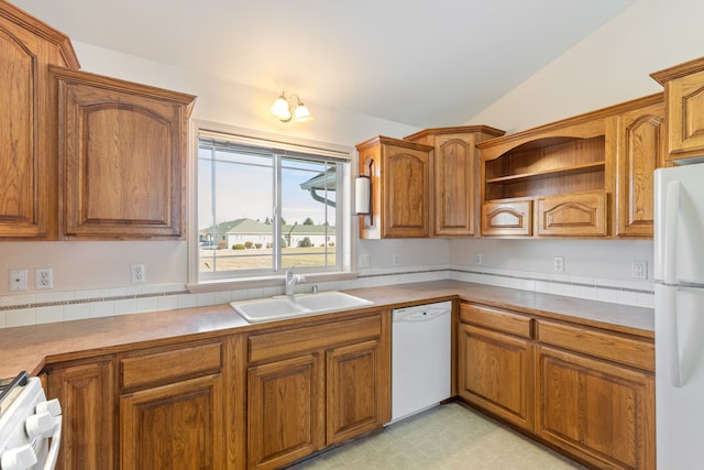 kitchen featuring light floors, brown cabinetry, a sink, vaulted ceiling, and white appliances