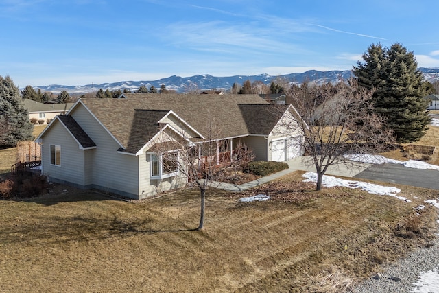 view of front of property featuring a shingled roof, a front yard, a mountain view, and an attached garage