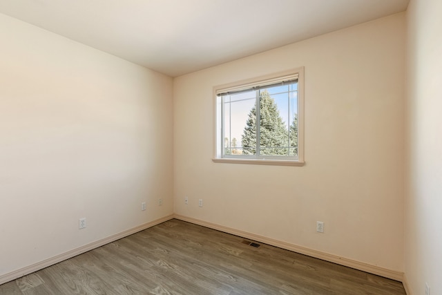 unfurnished room featuring wood finished floors, visible vents, and baseboards