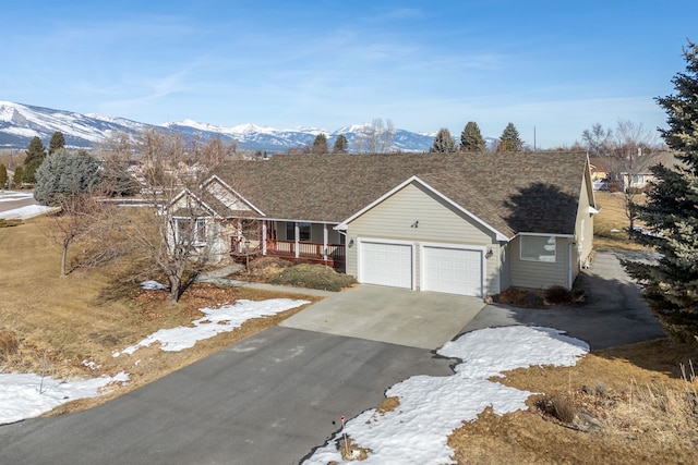 view of front of house with an attached garage, covered porch, a mountain view, and concrete driveway