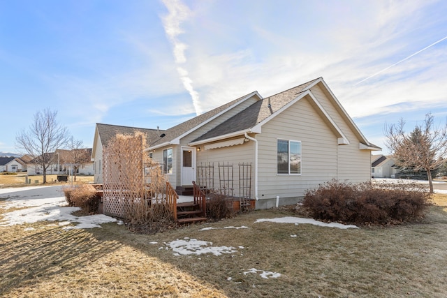 view of home's exterior featuring roof with shingles and a wooden deck