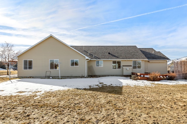 snow covered property with roof with shingles