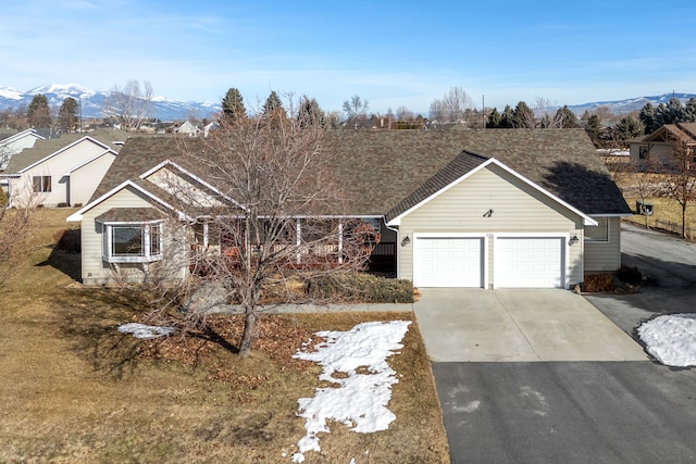 ranch-style home featuring driveway, an attached garage, and a mountain view