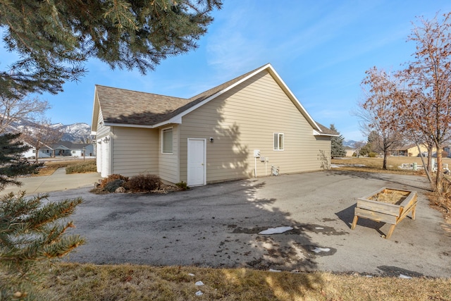 view of property exterior featuring driveway and roof with shingles