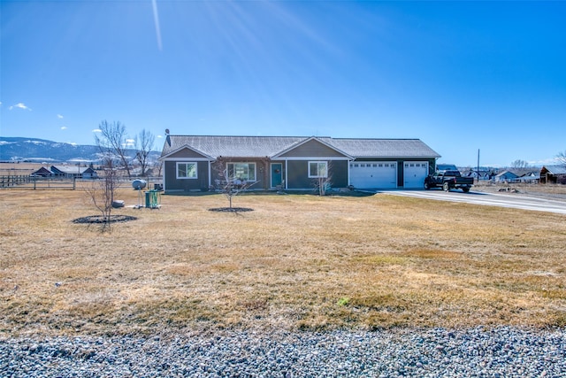 view of front facade featuring an attached garage, driveway, fence, and a front lawn