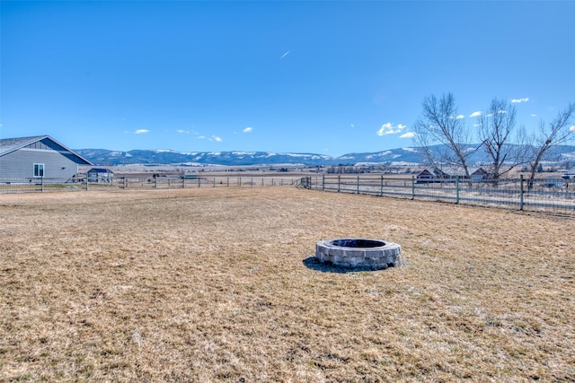 view of yard with an outdoor fire pit, a rural view, fence, and a mountain view