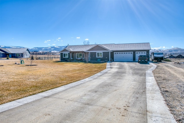 ranch-style home with driveway, an attached garage, fence, a mountain view, and a front lawn