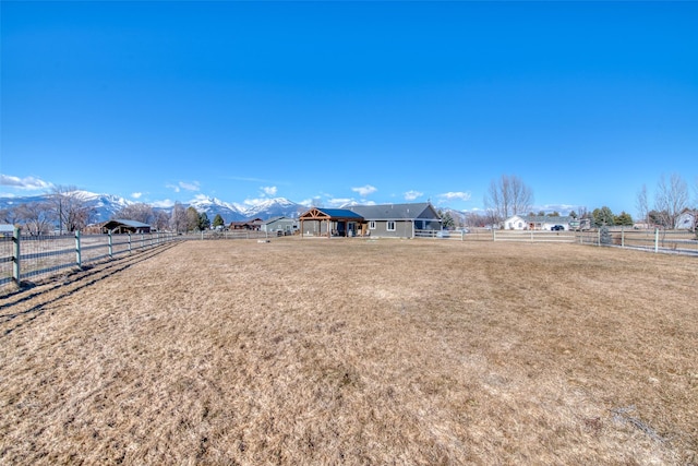 view of yard with an enclosed area, a rural view, fence, and a mountain view