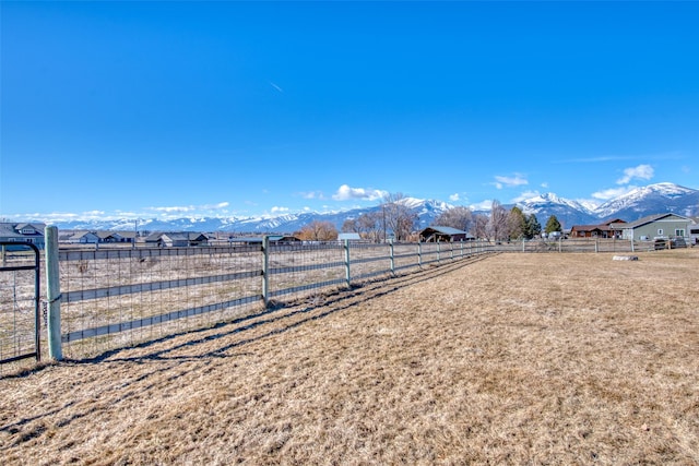 view of yard featuring fence, a mountain view, and a rural view