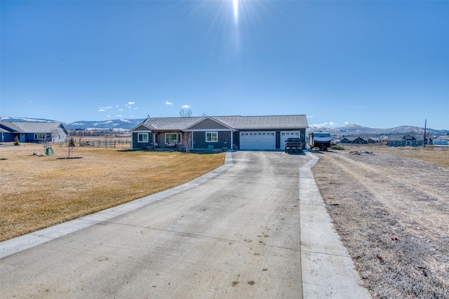 ranch-style home with a garage, driveway, a mountain view, and a front yard