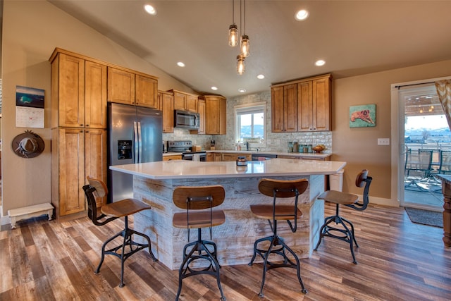 kitchen featuring lofted ceiling, stainless steel appliances, backsplash, and light wood-style floors