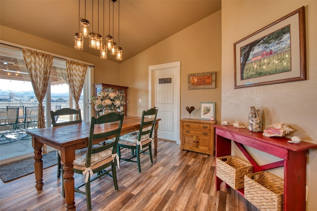 dining space with a notable chandelier, vaulted ceiling, and wood finished floors