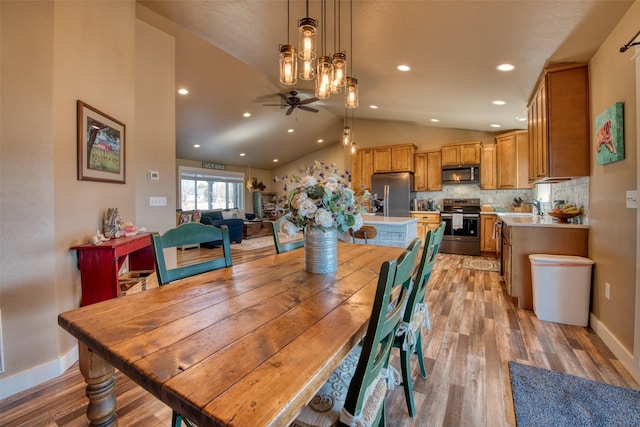 dining area featuring vaulted ceiling, ceiling fan, light wood-type flooring, and baseboards