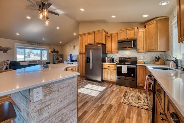 kitchen featuring lofted ceiling, stainless steel appliances, a sink, light countertops, and light wood-type flooring